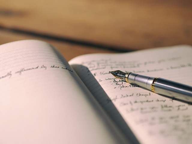 person reflecting while writing in journal at wooden desk with plants